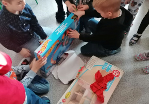 Dzieci odpakowują prezenty od Mikołaja.